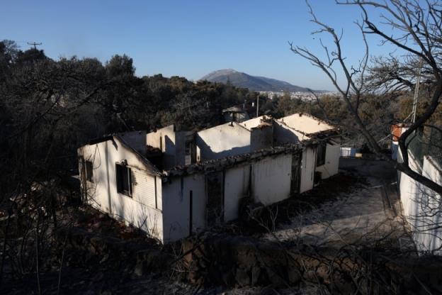 A white house is blackened with soot and its roof is missing.
